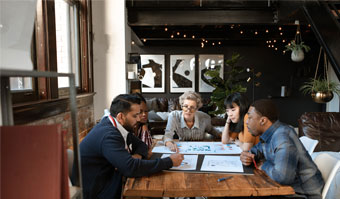 Group of people seating at a table, going over some drawings